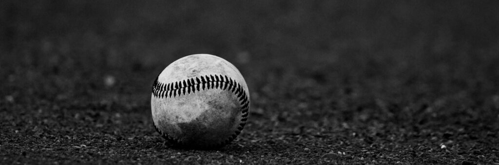 A monochrome image of a baseball resting on a textured dark surface, perfect for sports themes.