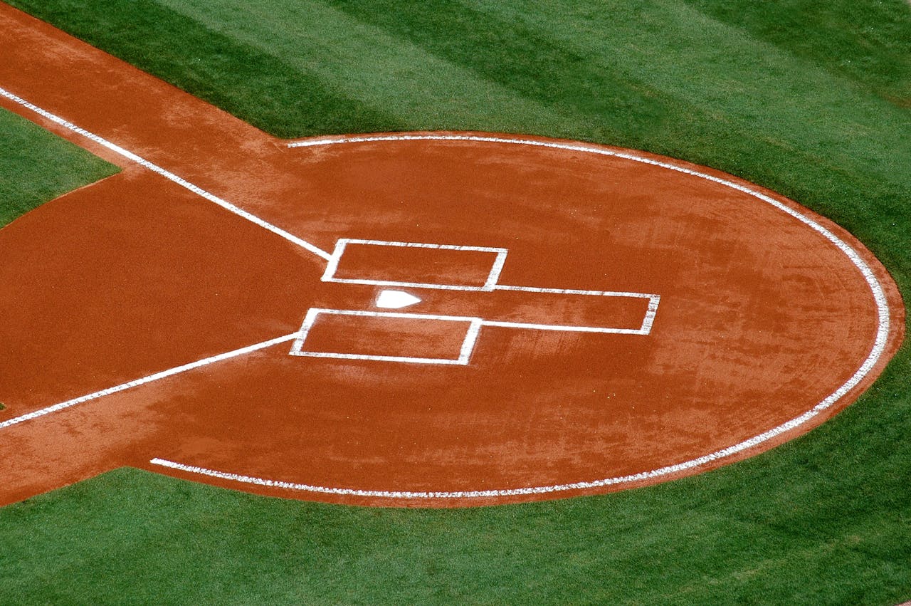 A top-down view of a baseball field's home plate area on a sunny day.