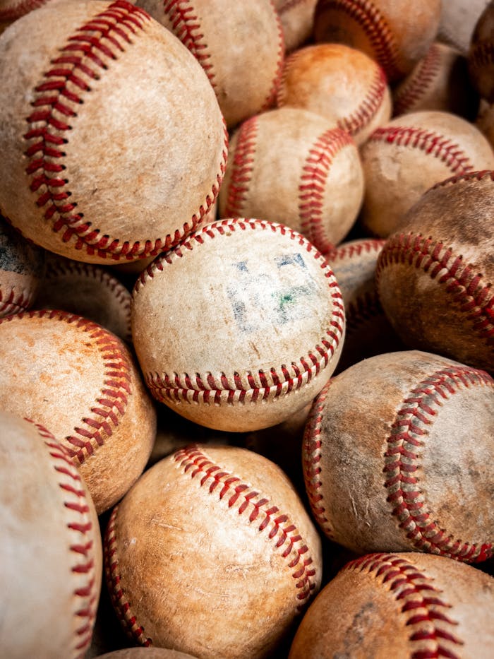 A close-up of a pile of vintage baseballs with worn texture and red stitches.